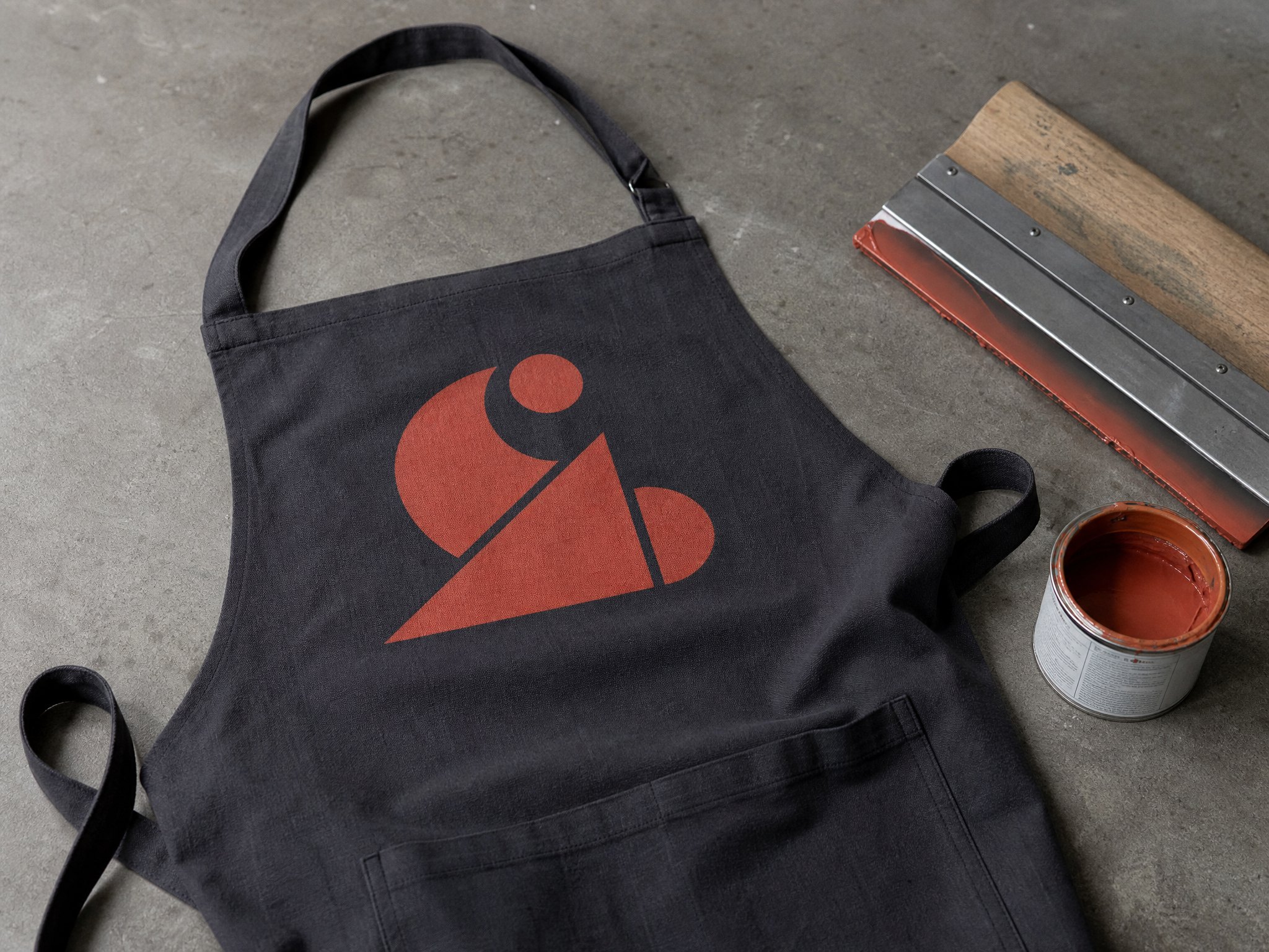 Freshly printed logo in terracotta on a dark bistro apron in the print workshop